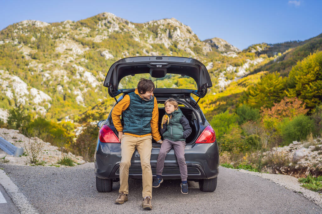 Dad and son are resting on the side of the road on a road trip. Road trip with children concept - Photo, Image