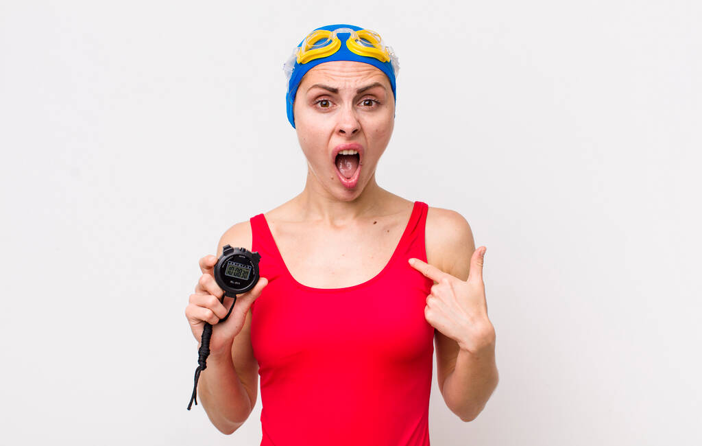 young pretty woman  looking shocked and surprised with mouth wide open, pointing to self. swimmer with a timer - Foto, Imagen
