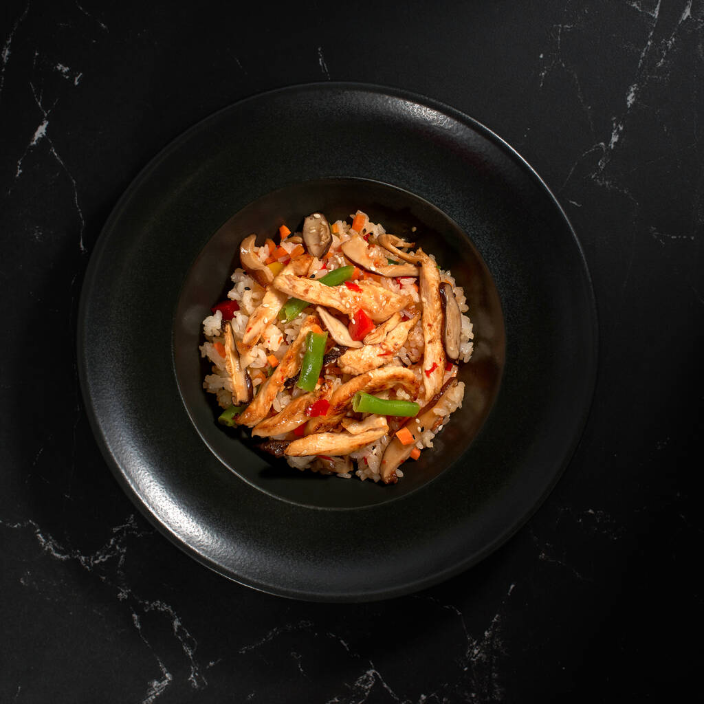 Chicken teriyaki with garnish Japanese rice, sweet pepper, shiitake mushrooms on a dark background. Asian cuisine, Wok menu, top view. - Photo, image