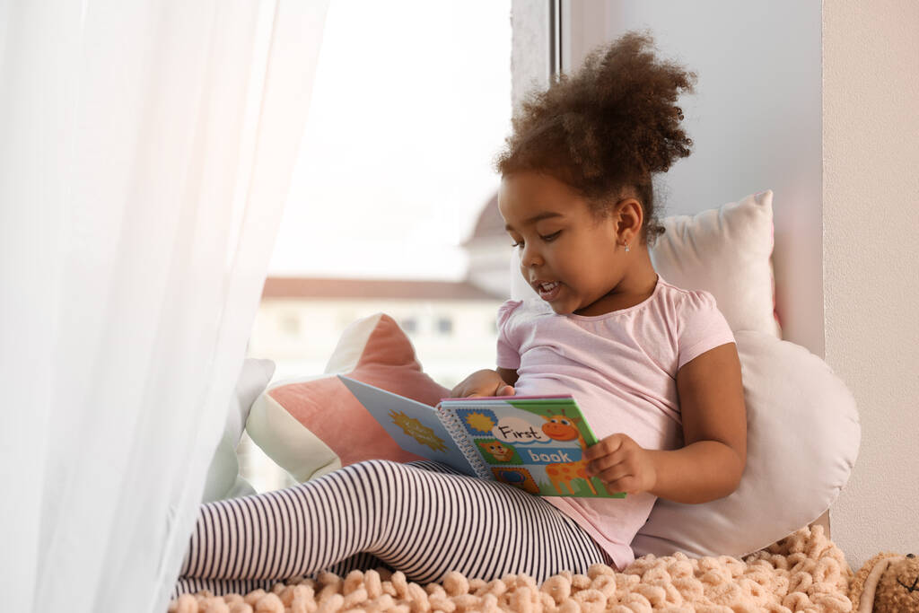 African American girl reading book at home - Foto, imagen