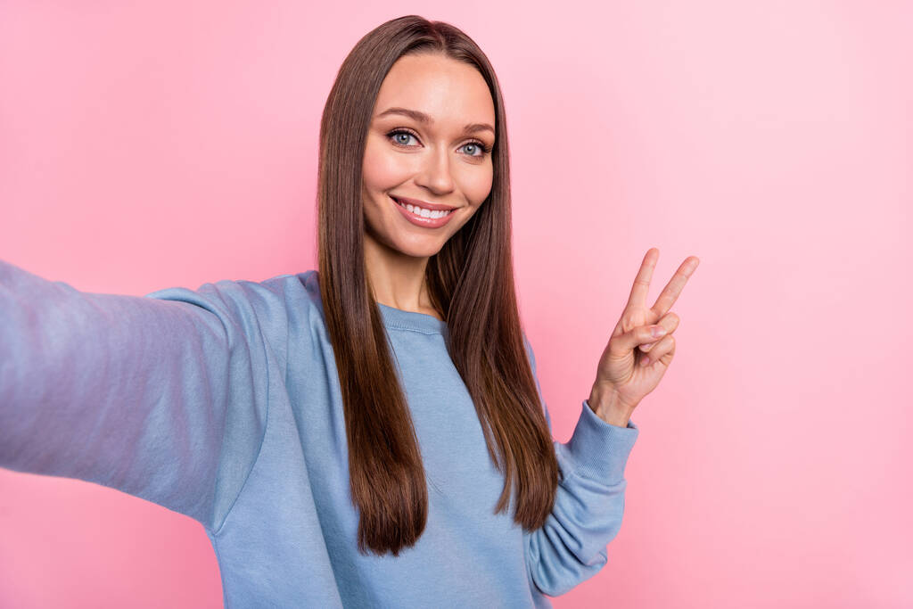Selbstporträt von attraktiven mädchenhaft fröhlich Mädchen zeigt V-Zeichen Rest isoliert über rosa Pastellfarbe Hintergrund - Foto, Bild