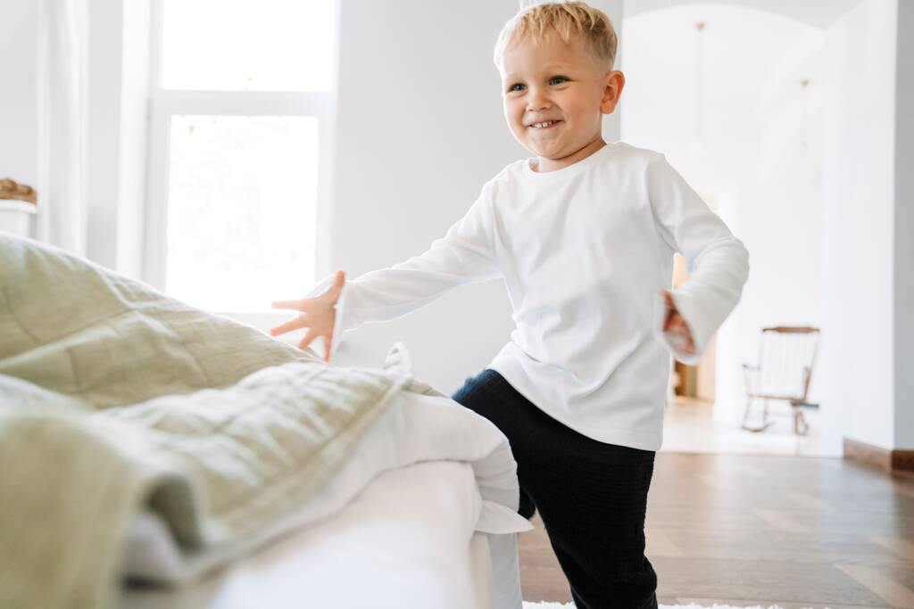 Bílé blondýny chlapec nosí domácí oblečení se směje a hraje uvnitř - Fotografie, Obrázek