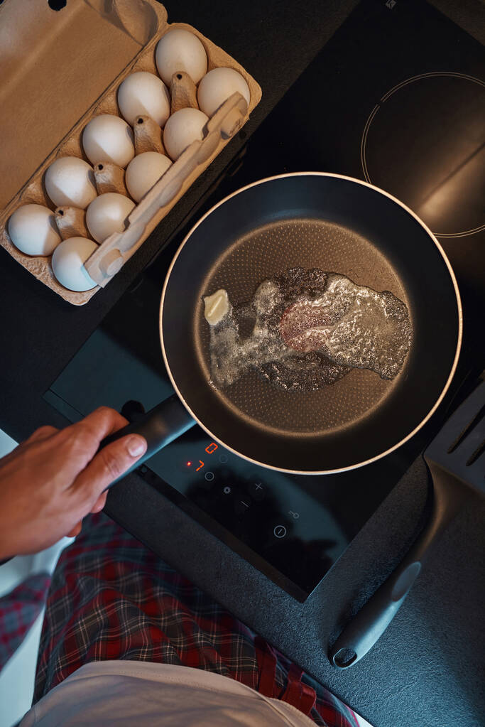 Άντρας κρατήστε τηγάνι με βούτυρο τήξη στην ηλεκτρική κουζίνα - Φωτογραφία, εικόνα