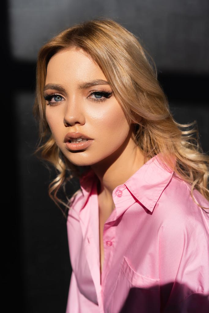 portrait of young woman in pink shirt looking at camera on black background - Foto, Imagem