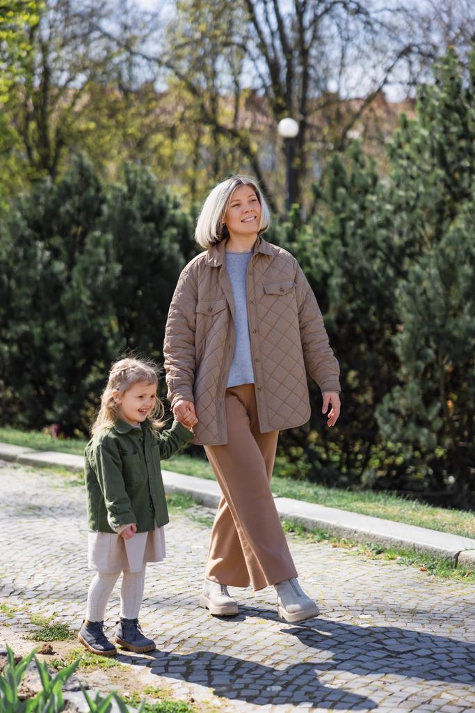 teljes hossza boldog és elegáns nő lánya séta a tavaszi parkban - Fotó, kép