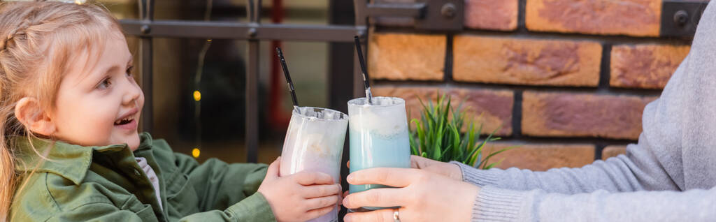 moeder en kind toasten met een bril van milkshake in cafe buiten, banner - Foto, afbeelding