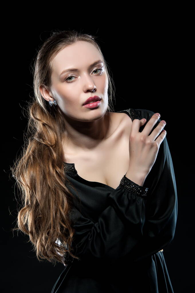 Schöne sexy brünette Mädchen posiert auf einem schwarzen Hintergrund in einem Abendkleid - Foto, Bild