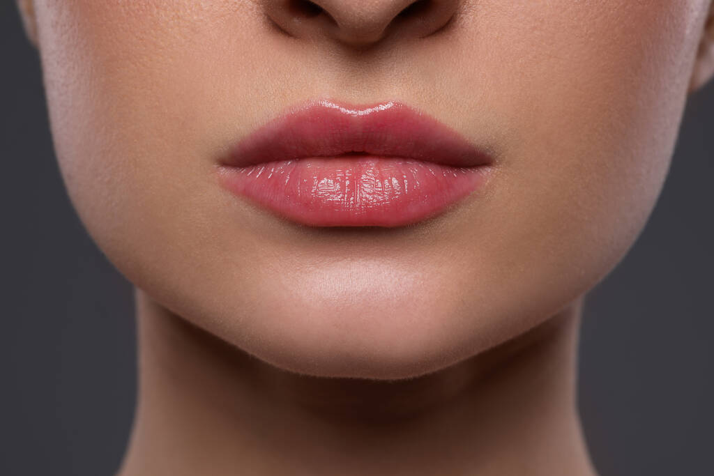 Jeune femme avec de belles lèvres sur fond gris, gros plan - Photo, image