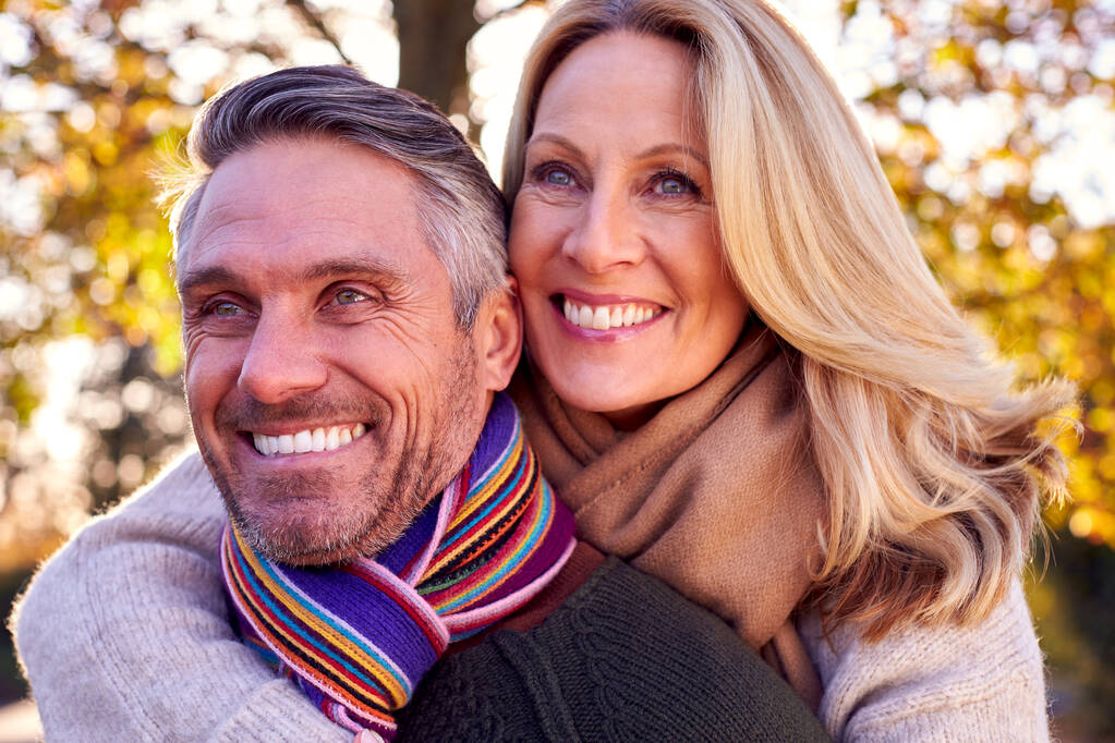 Loving Mature Woman Hugging Man From Behind As Retired Couple Walk Through Autumn Countryside - Photo, Image