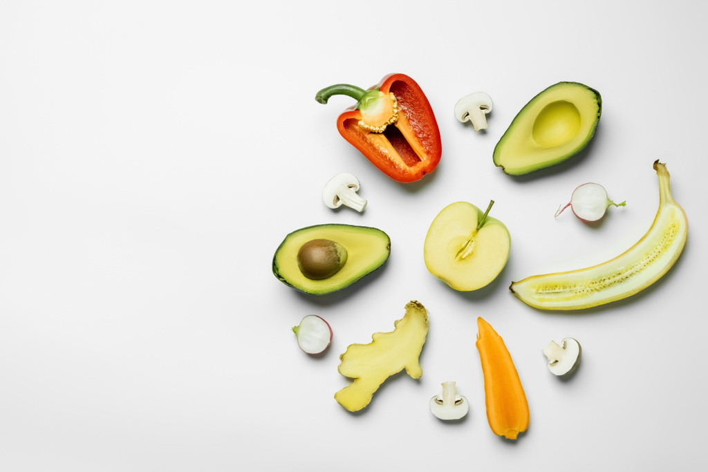 Плоский лежак з нарізаними свіжими фруктами та овочами на білому тлі
 - Фото, зображення