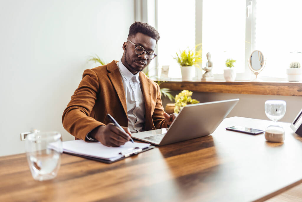 Focado jovem empresário africano estudar on-line assistindo webinar podcast em laptop ouvir aprendizagem curso de educação conferência chamada fazer notas sentar na mesa de trabalho, conceito de aprendizagem eletrônica - Foto, Imagem