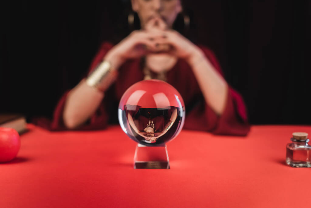 Cropped view of magic orb near blurred fortune teller isolated on black  - 写真・画像