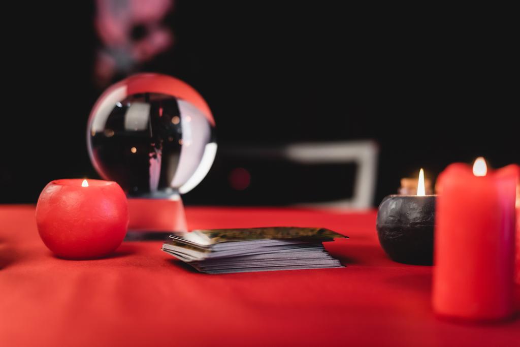 Tarot cards near burning candles and blurred orb on black  - Fotografie, Obrázek