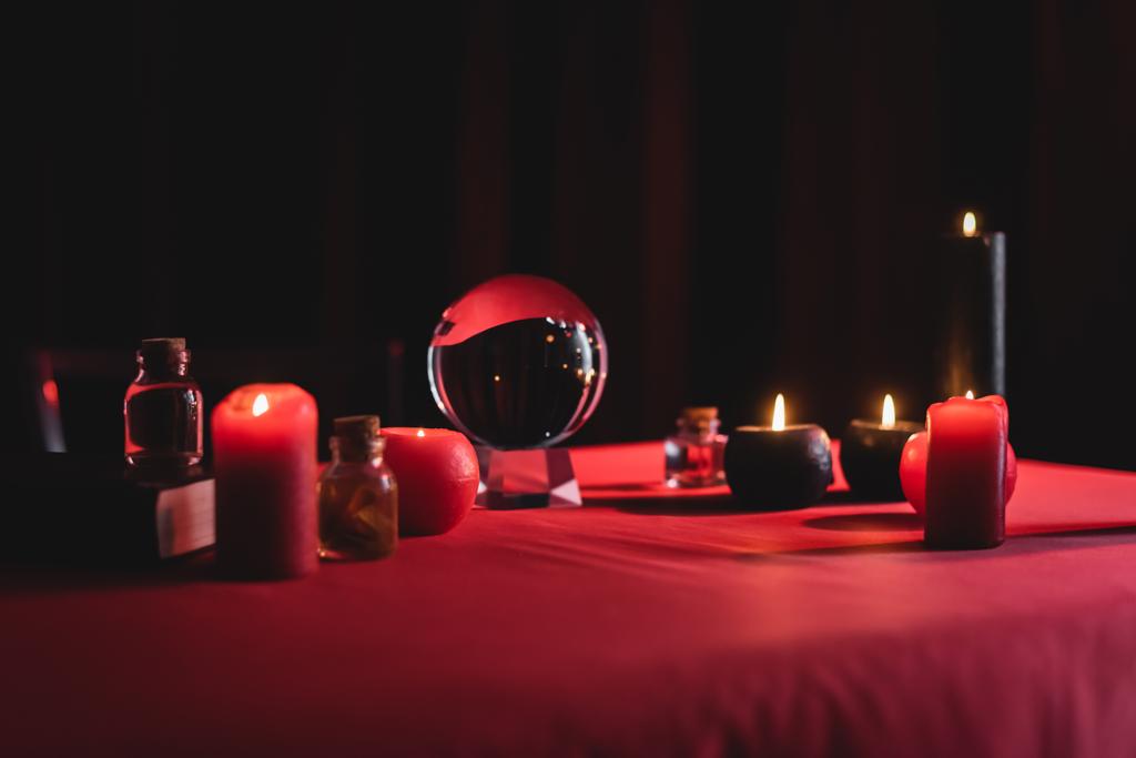 Magic orb near burning candles on table isolated on black  - Photo, Image