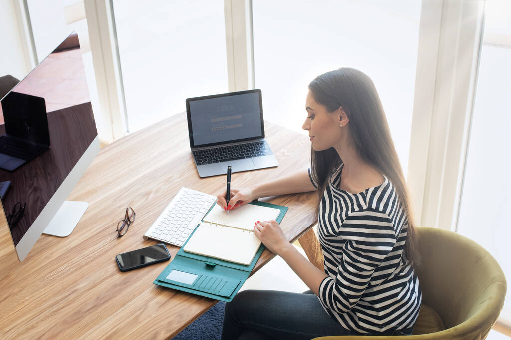 Businesswoman sitting at desk and making notes while working from home. Home office. - Φωτογραφία, εικόνα