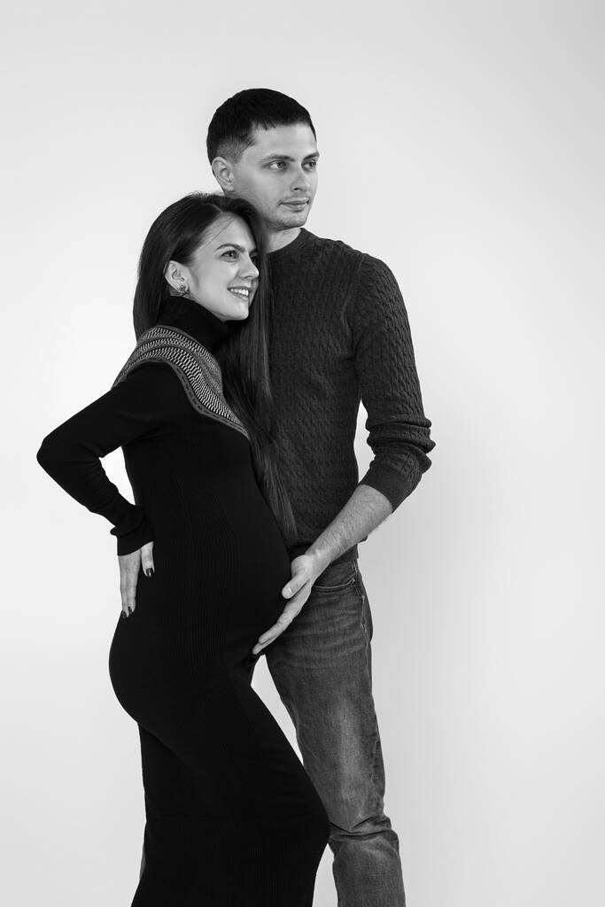 Чоловік обіймає вагітну дружину і торкається живота
 - Фото, зображення