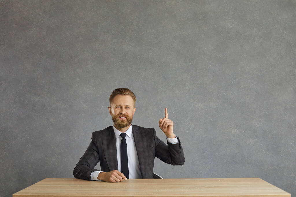 Smiling positive businessman in formal suit have idea sit at desk studio shot - Фото, изображение