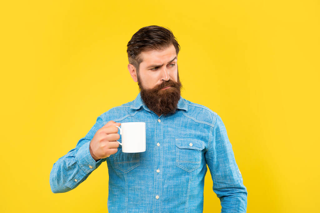 Serious caucasian guy holding mug yellow background, tea break - Photo, Image
