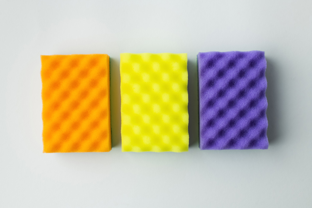 top view of orange, yellow and purple sponges on grey background - Foto, imagen