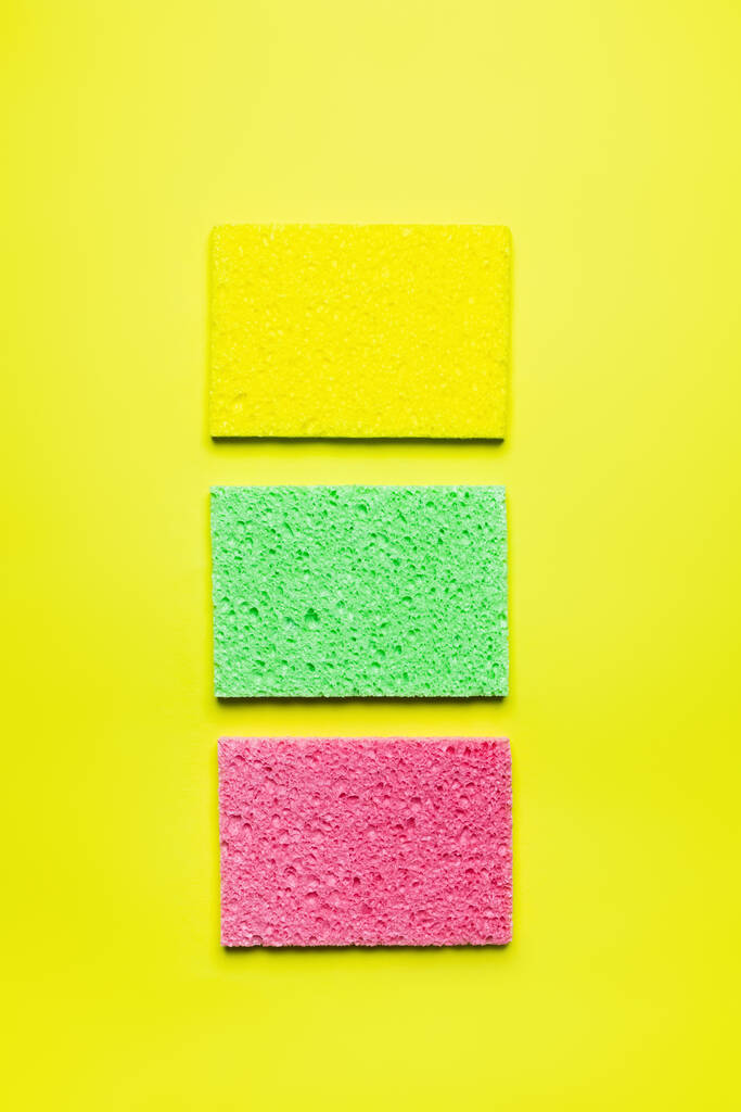top view of bright multicolored sponge cloths on yellow background - Foto, imagen