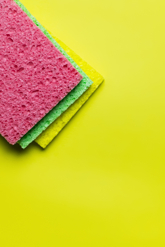 top view of bright multicolored sponge rugs on bright yellow background - Foto, afbeelding