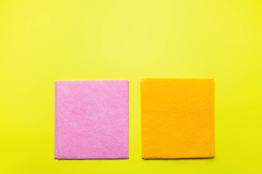 верхний вид ярко-розовых и оранжевых посуды на желтом фоне - Фото, изображение