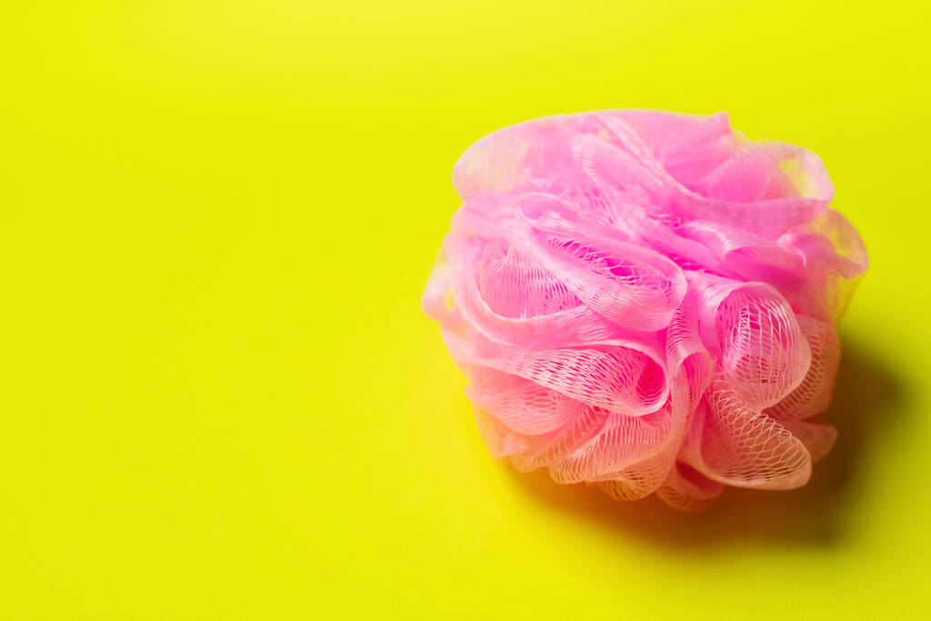 top view of pink mesh washcloth on bright yellow background - Photo, Image