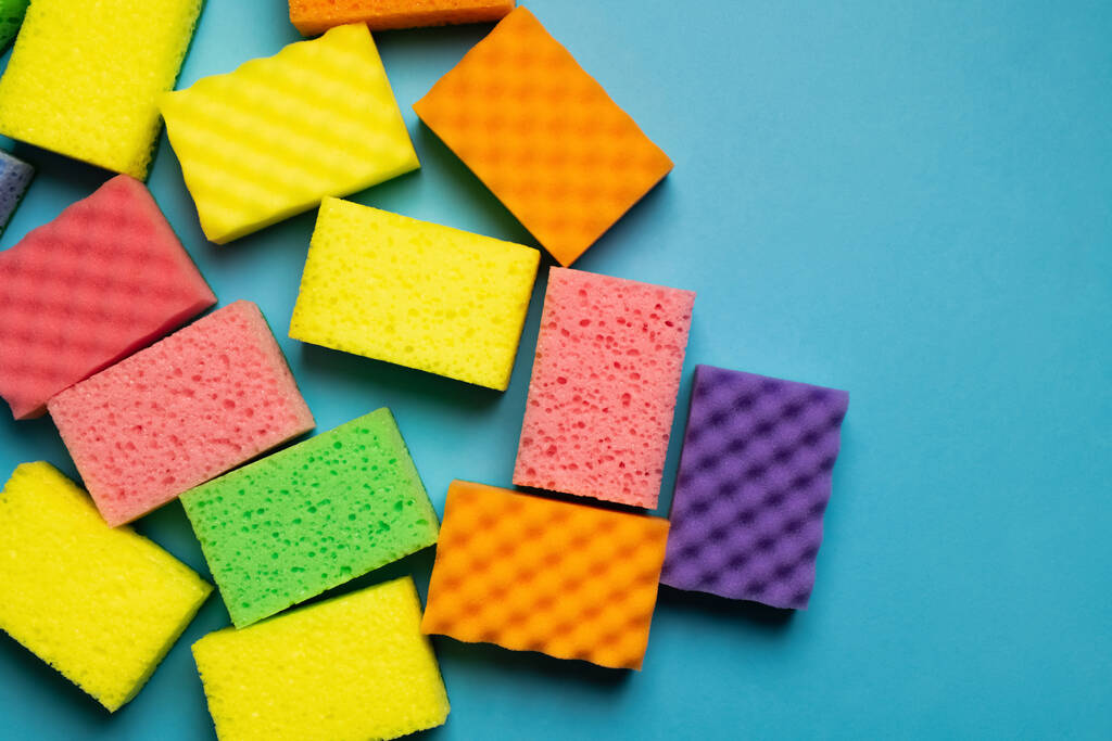 plenty of different multicolored sponges on blue background, top view - 写真・画像