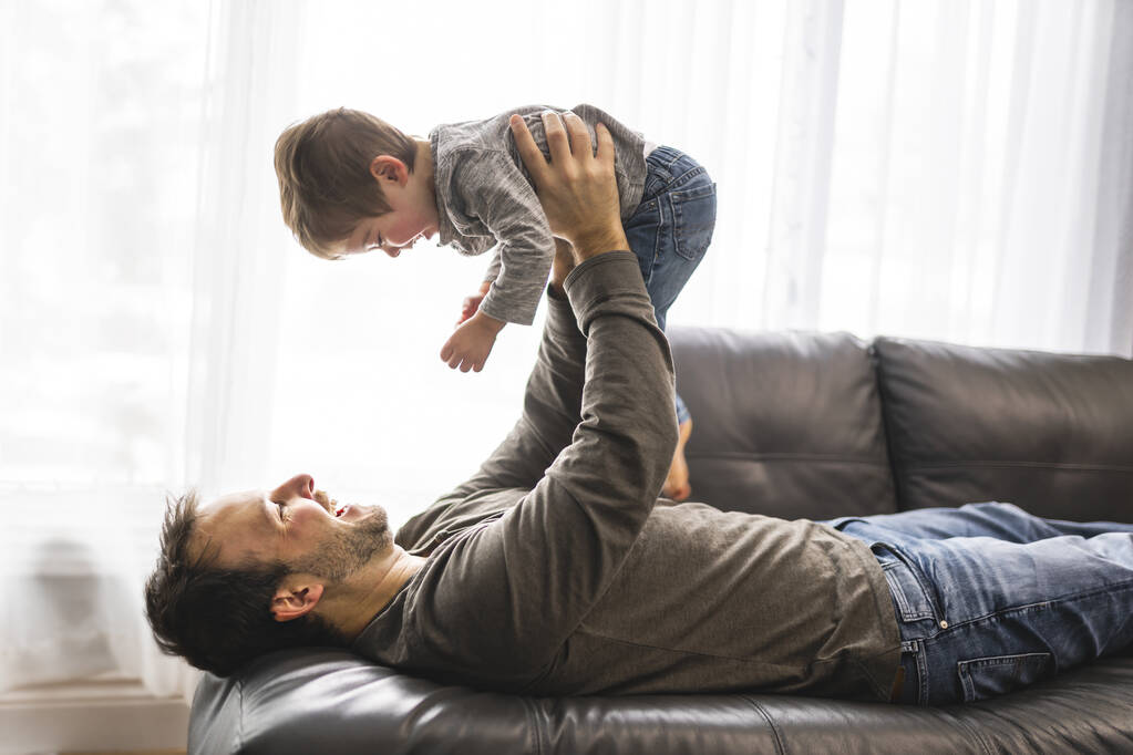 Portrait of little boy with father having fun on sofa - Photo, Image