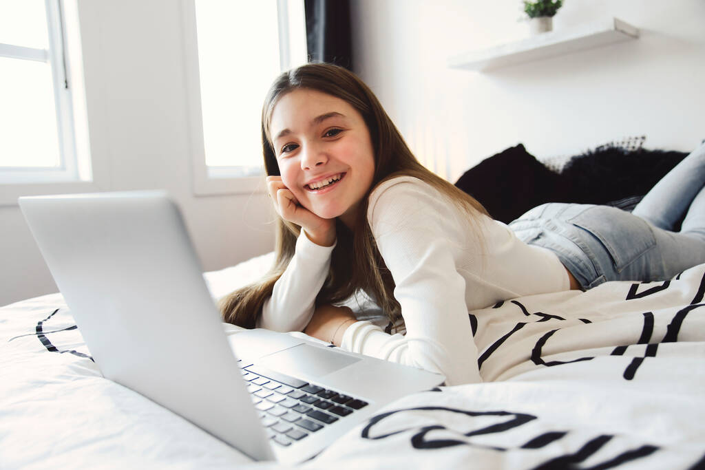 leuk tiener meisje met behulp van een computer in haar slaapkamer. - Foto, afbeelding