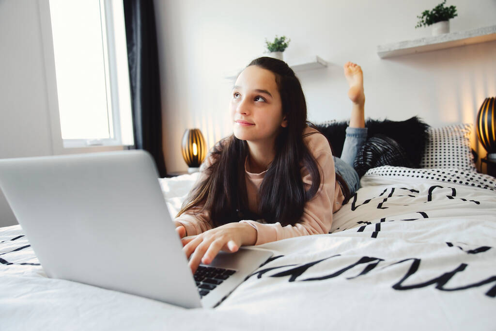 Nice teenage girl using a computer in her bedroom. - Zdjęcie, obraz