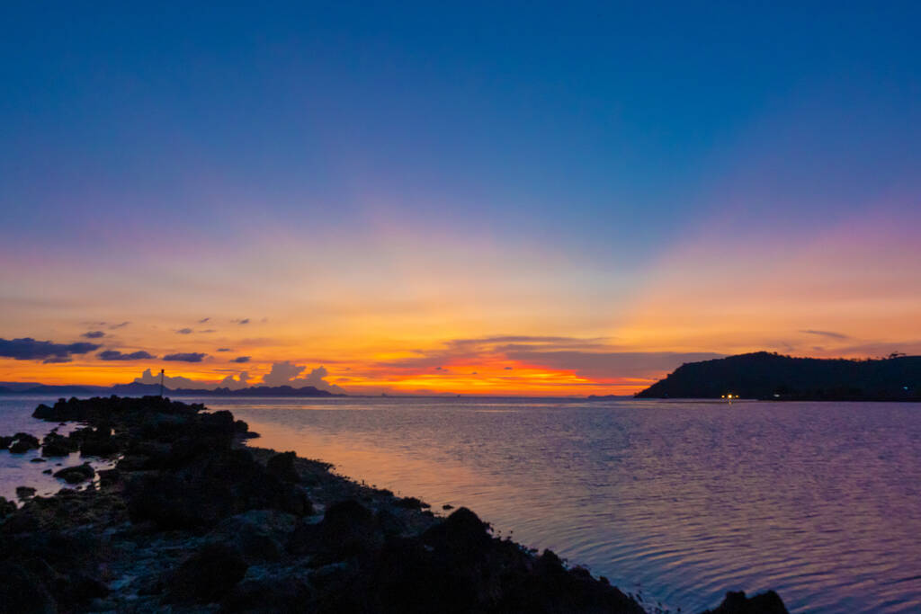 海岸沿いの素晴らしい夕日の風景、夕日の空の色、水の中の島のシルエット。信じられない熱帯の夕日. - 写真・画像