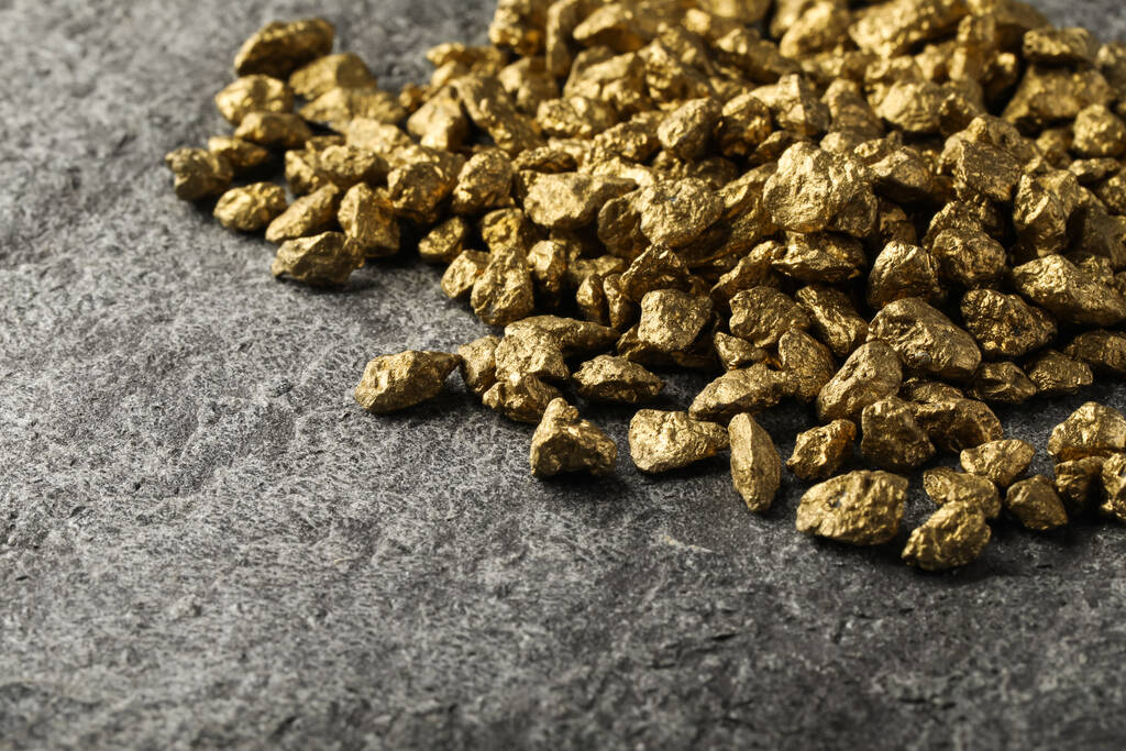 Pile of gold nuggets on grey table, space for text - Fotó, kép