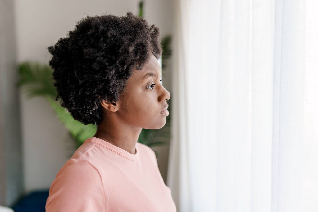 Pensive sad young African American woman look in window - Photo, Image