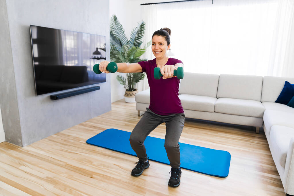 Attractive Fit woman Exercise at home on the living room with dumbell on hand - Foto, imagen