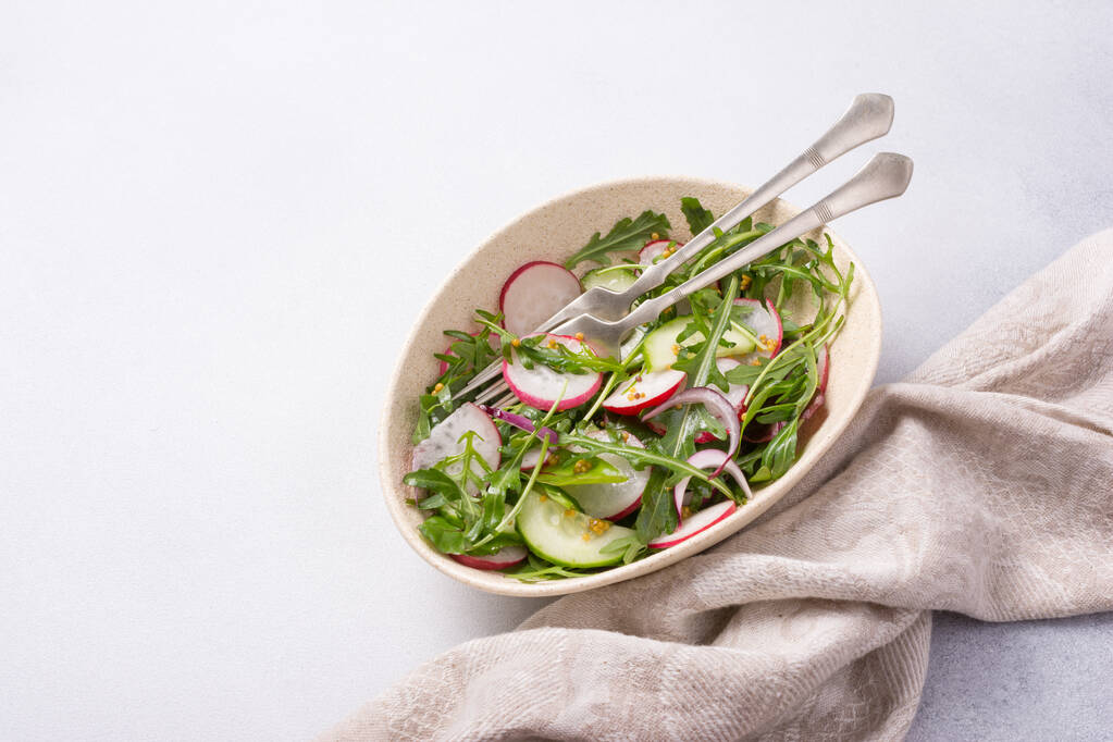 Healthy and tasty vegan food. Top view of light salad with radish, cucumber, onion, fresh green leaves and mustard sause on grey concrete background - Fotoğraf, Görsel