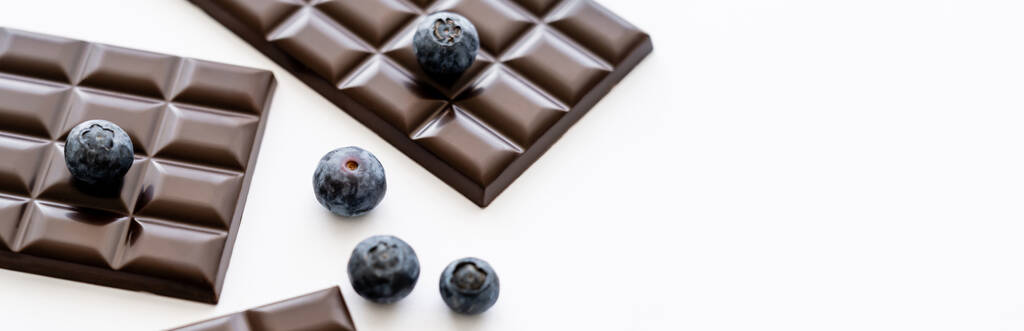 Close up view of fresh blueberries and chocolate bars on white background, banner  - Zdjęcie, obraz
