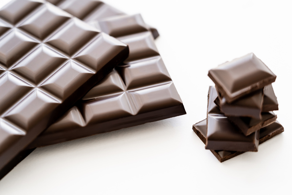 Close up view of bars and pieces of dark chocolate on white background  - Foto, Bild