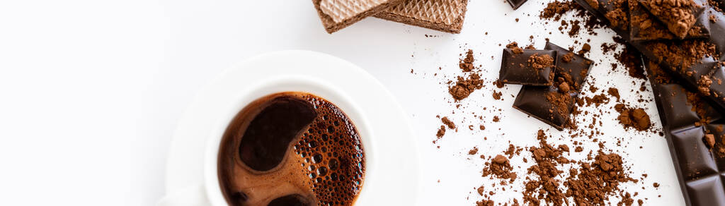 Top view of cup of coffee, waffles and brown chocolate on white background, banner  - Photo, Image