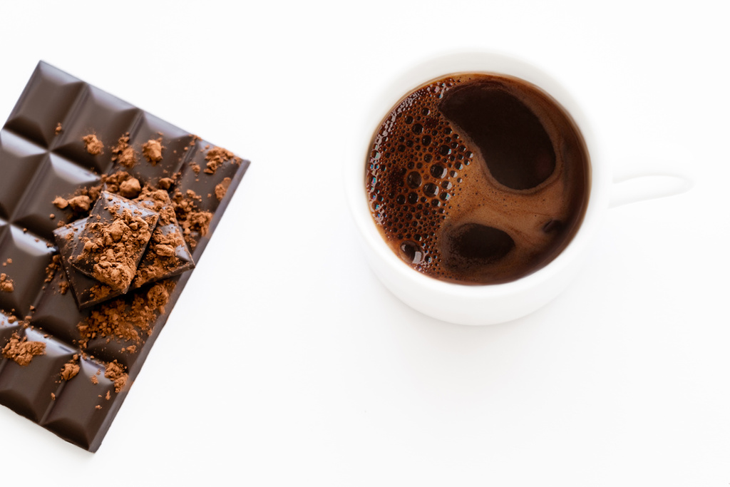 Koyu çikolatanın yanında beyaz arka planda kakaolu bir fincan kahvenin üst görüntüsü.  - Fotoğraf, Görsel