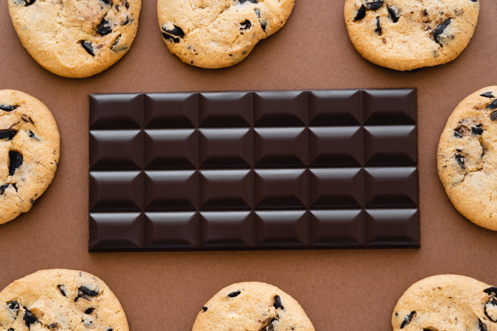 Vista superior de la barra de chocolate en marco de galletas sobre fondo marrón  - Foto, imagen