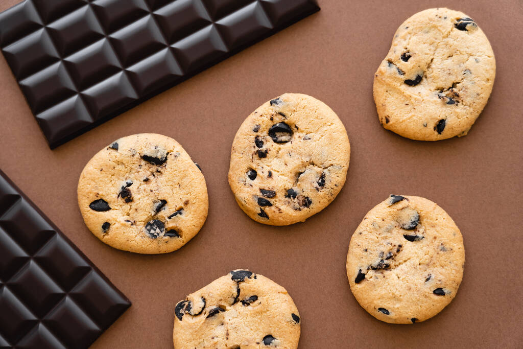 Вид зверху на шоколадні батончики та печиво на коричневому фоні
  - Фото, зображення
