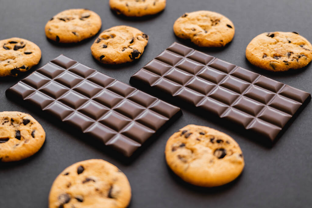 Barres de chocolat noir près des biscuits sur fond noir - Photo, image