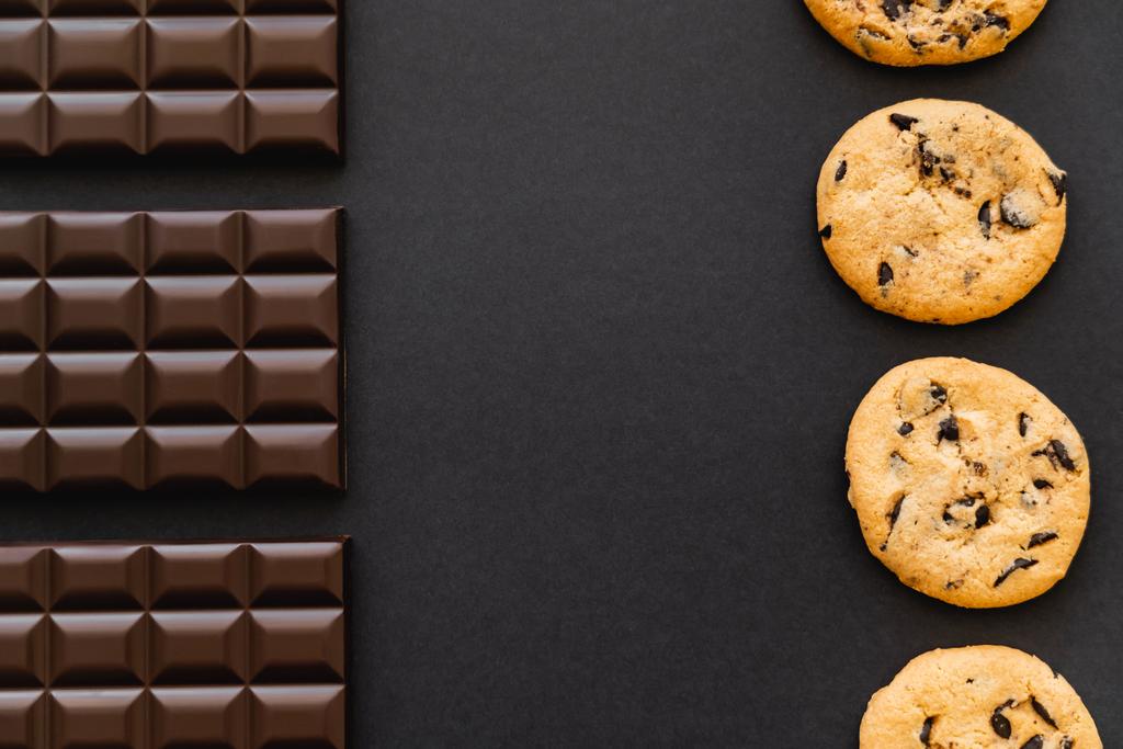 Flat lay with chocolate bars and cookies on black background - Fotografie, Obrázek