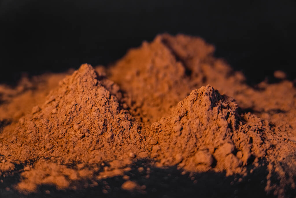 Close up view of dry cocoa powder on black background  - Foto, Imagen