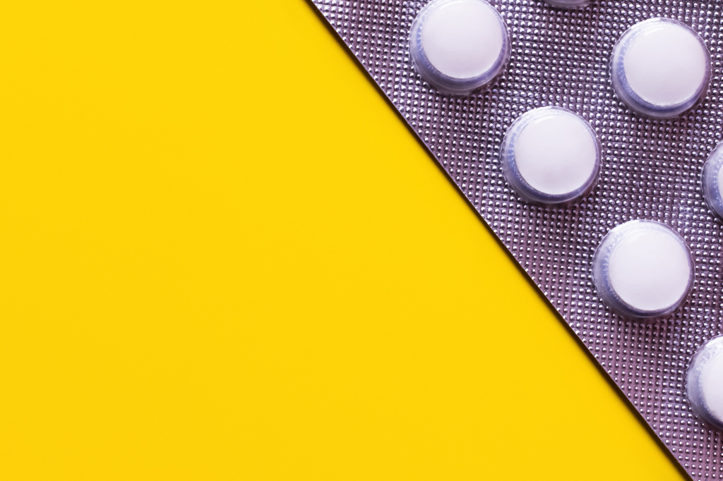 vista de cerca del blister con píldoras blancas aisladas en amarillo con espacio para copias - Foto, imagen