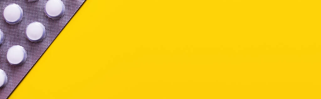 vista de perto da embalagem blister com comprimidos brancos isolados em amarelo, banner - Foto, Imagem