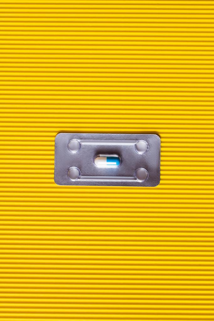 widok z góry blistra z kapsułką z antybiotykami na teksturowanym żółtym tle - Zdjęcie, obraz
