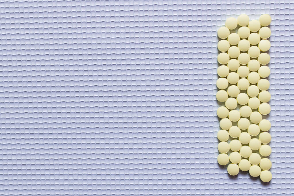 flat lay of yellow round shape medication on white textured background - Zdjęcie, obraz