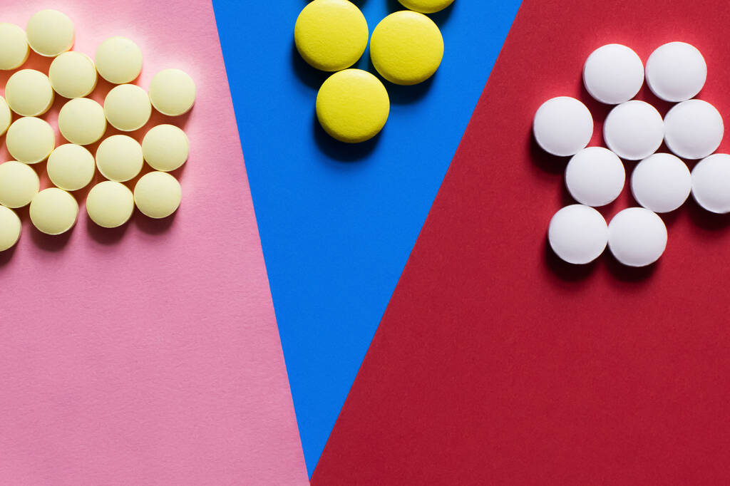 top view of round shape white and yellow pills on colorful background - 写真・画像